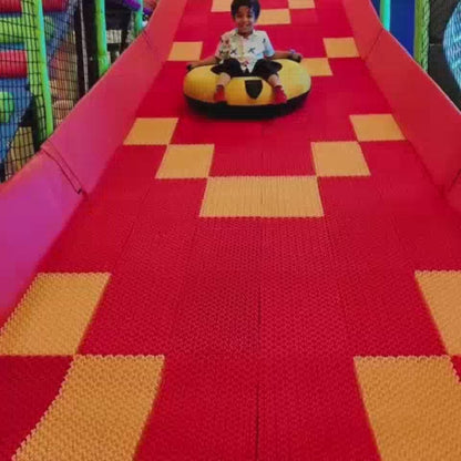 A young boy enjoys a vibrant indoor playground, sliding down colorful tubes, playing in a ball pit, and navigating obstacle courses. The atmosphere is lively and fun, with various soft play equipment and interactive games designed for children.