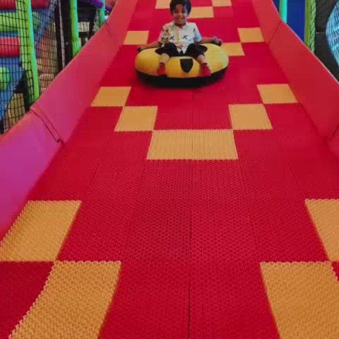 A young boy enjoys a vibrant indoor playground, sliding down colorful tubes, playing in a ball pit, and navigating obstacle courses. The atmosphere is lively and fun, with various soft play equipment and interactive games designed for children.