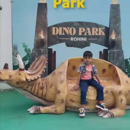 A young child poses on a dinosaur bench at Dino Park Rohini, followed by a glimpse of a gorilla statue and various dinosaur models. Later, people experience a vortex tunnel and a 7D ride, enjoying immersive visual attractions.