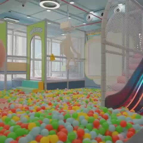 A vibrant indoor play area filled with colorful balls, slides, and play structures. Children of various ages enjoy activities like sliding, jumping on trampolines, and playing pretend in themed areas like a fire station and police station. The atmosphere is lively and fun, with families interacting and children engaged in playful exploration.