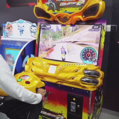 A vibrant arcade buzzes with activity as people of all ages enjoy various games. Children laugh while playing a duck-themed shooting game, while others are engrossed in racing simulators and a claw machine filled with plush toys. A teenager experiences virtual reality, immersed in a digital world.