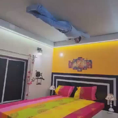 A young man performs impressive handstands and acrobatic feats in various rooms of a house, including a bedroom, kitchen, and bathroom, creating a surreal, gravity-defying spectacle. The vibrant colors of the rooms and the man's athletic prowess contribute to a playful and astonishing atmosphere.