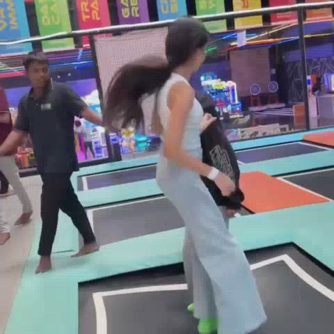 A group of young people enjoys a vibrant indoor amusement park filled with trampolines, a ball pit, arcade games, bumper cars, and a bowling alley. The atmosphere is energetic and fun, with colorful decorations and exciting attractions.