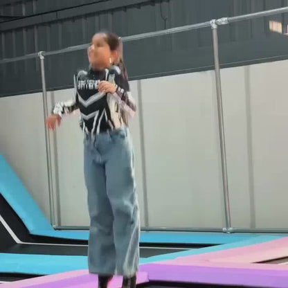 A young girl enjoys a variety of interactive exhibits at an indoor amusement park. She bounces on trampolines, swings on a rope, plays with a ball machine, and tries a "stringless harp." The atmosphere is lively and fun, with colorful attractions and other children present.