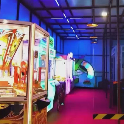 A couple enjoys a vibrant arcade, playing bumper cars, dance games, and VR simulations. The neon-lit environment buzzes with energy, offering a fun-filled experience for young adults. They also try their luck at claw machines and engage in competitive air hockey.