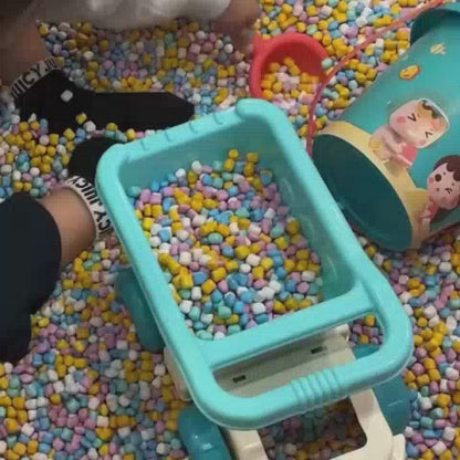 Children of various ages enjoy a vibrant indoor play area filled with ball pits, a carousel, interactive screens, and climbing structures. The atmosphere is lively and playful, with bright colors and engaging equipment designed for fun and exploration.