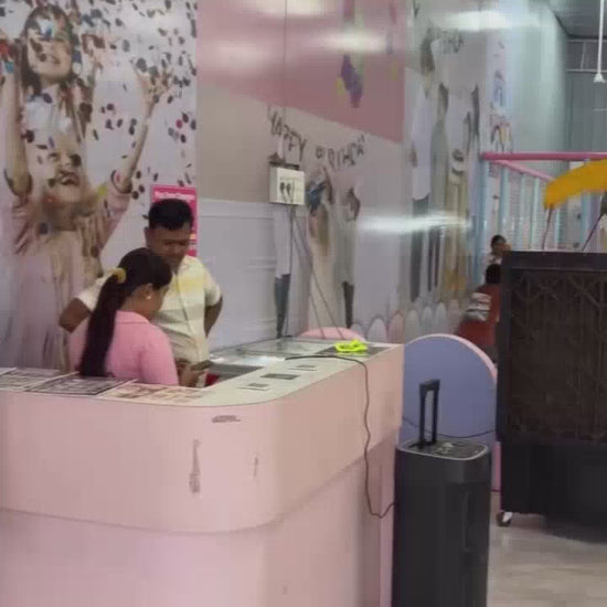 Children of various ages enjoy a vibrant indoor play area with slides, a ball pit, a climbing wall, and a trampoline. The colorful environment is designed for fun and active play, with parents supervising.