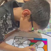Children are engaged in a colorful art project, painting on various surfaces like paper and pottery. The setting appears to be a home or classroom, filled with art supplies and a creative atmosphere. The children, likely elementary school age, are focused and enjoying their artistic endeavors.