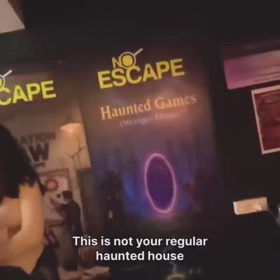 A group of young adults participates in a "Haunted Games" escape room experience. The dimly lit environment features spooky decorations, puzzles, and sound effects, creating a thrilling and immersive atmosphere. Participants use a walkie-talkie to communicate with the game master as they solve mysteries within the hour-long challenge.