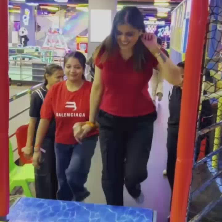 A group of young adults and children enjoy a variety of indoor amusement park activities, including trampolines, bumper cars, go-karts, bowling, and a laser maze. The vibrant, neon-lit environment creates a fun and energetic atmosphere as participants engage in playful challenges and races.