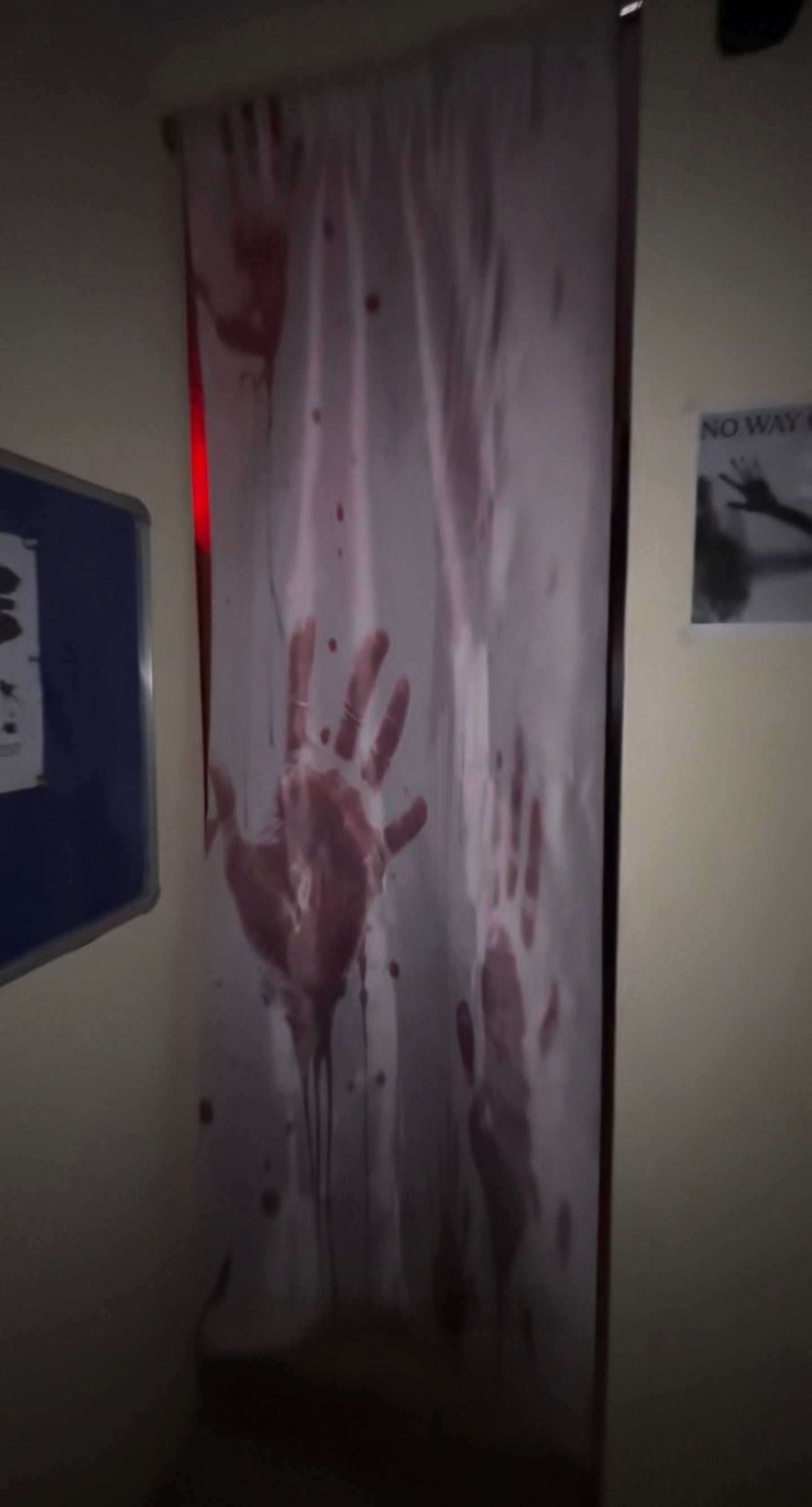 Curtain with bloody handprints and splatters illuminated by red light inside No Escape Room at Rajinder Nagar Delhi