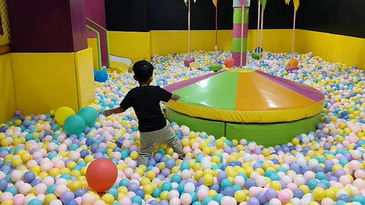 Child playing in colorful ball pit with suspended swings at Skyjumper Trampoline Park The Opulent Mall Ghaziabad